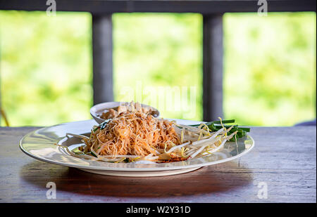 Spaghettini fritti con molla di cipolla e di germogli di soia sulla piastra bianca con guarnire. Foto Stock