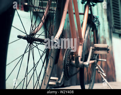 Incredibile close up vecchio anteriore di bicicletta di antica casa, la ruota di bicicletta la ruggine, danneggiata con sfondo sfocato in tono vintage a China Town, Vietnam Foto Stock