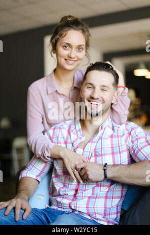 Felice giovane marito seduto con una bella moglie a casa. Concetto di trascorrere del tempo insieme e relazioni. Foto Stock