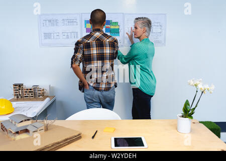 Maschio e femmina di architetti a discutere su un piano architettonico in office Foto Stock