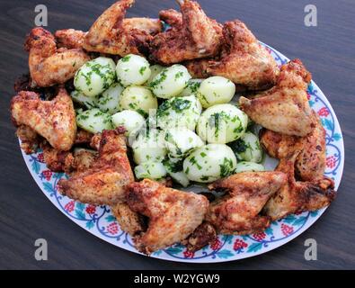 Croccante di ali di pollo con baby prezzemolo e patate Foto Stock