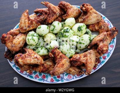 Croccante di ali di pollo con baby prezzemolo e patate Foto Stock