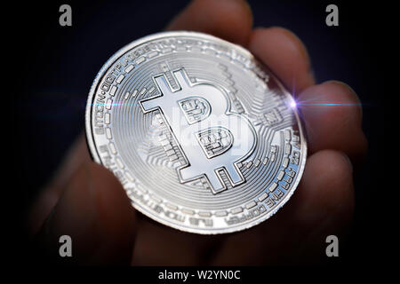 Dito holding Bitcoin coin, moneta virtuale Foto Stock