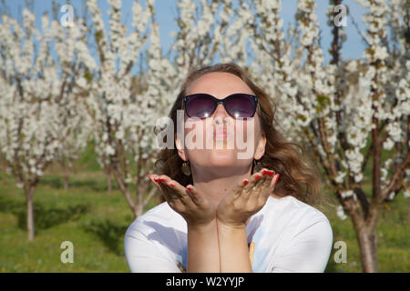 Giovane donna in occhiali da sole su un campo con rigogliosi alberi di mandorle. La Francia. Foto Stock