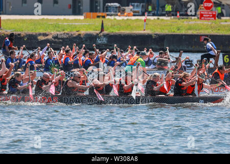 Dragon Boat racing team competere a Londra Hong Kong Dragon Boat Festival in splendido sole, Royal Docks in Londra, Regno Unito Foto Stock