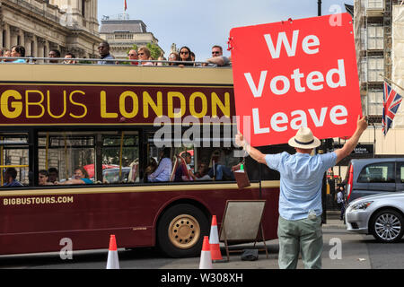 Un lasciare e sostenitore Brexit detiene un 'abbiamo votato lasciare targhetta" verso i turisti su un bus in Westminster, Londra, Regno Unito Foto Stock