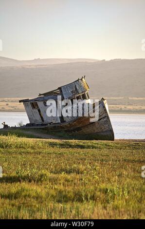 Colpo verticale di una nave arrugginita naufragata sulla costa di un fiume Foto Stock