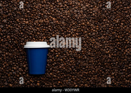 Blue tazza monouso per andare, sullo sfondo dei chicchi di caffè con spazi vuoti per il testo. Foto Stock