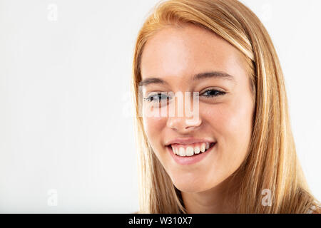 Sorridenti giovane donna con capelli lunghi biondi grinning alla fotocamera, vicino il colpo di testa isolata su bianco Foto Stock