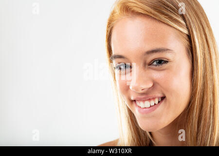 Abbastanza gentile giovane donna con un vivace sorriso in un vicino la testa mozzata shot isolato su bianco con spazio di copia Foto Stock