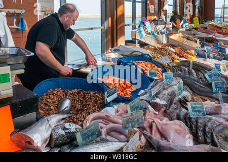 Contatore con pesce fresco e gamberetti sul display al coperto Mercato del pesce al porto a località balneare di Port-en-Bessin, Calvados, Normandia, Francia Foto Stock