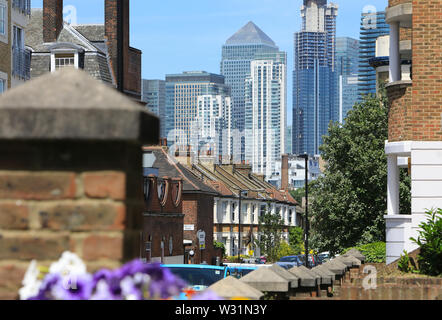 Case sulla East Ferry Road con Canary Wharf oltre, sull'Isola di cani, nella zona est di Londra, Regno Unito Foto Stock