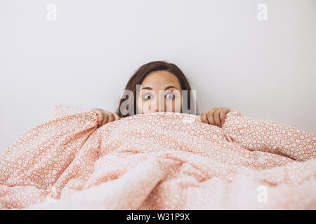 Ritratto di una bella ragazza che copre la faccia con una coperta. Foto Stock