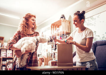 L'odore del cibo. Allegro shopping assistant sorridere mentre dando un po' di cibo per il cane a odore Foto Stock