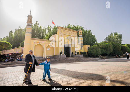 Kashgar, Cina. Xix Apr, 2019. Un anziano Uyghur uomo cammina con un bambino con la scuola uniforme su di fronte alla Moschea Id Kah e a Kashgar.La provincia dello Xinjiang si trova nella parte nord occidentale della Cina è la più grande provincia in Cina. La maggior parte della popolazione è di religione musulmana nello Xinjiang. Recentemente il governo cinese ha imposto una massiccia repressione di sicurezza nello Xinjiang, dove più di un milione di etnia uiguri e altri per la maggior parte delle minoranze musulmane sono creduti per essere mantenuto in una rete di internamento che Pechino descrive come ''istruzione professionale " centri " destinata a pers dello sterzo Foto Stock