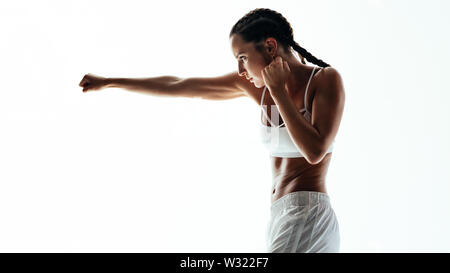 donna fitness che fa l'allenamento di boxe. Donna che pratica pugilato, lanciando un pugno davanti su sfondo bianco. Foto Stock