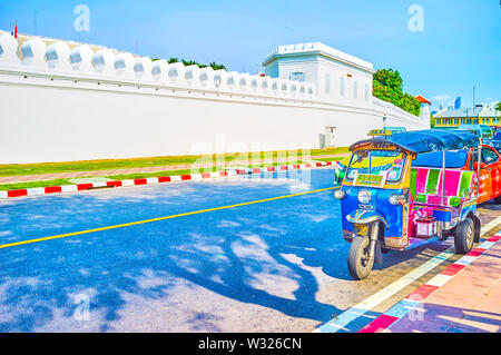 BANGKOK, Tailandia - 22 Aprile 2019: la linea di tuk-tuks parcheggiato all'ombra di alberi e attendere per i clienti presso le pareti del Grand Palace, su Aprile Foto Stock