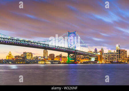 Philadelphia, Pennsylvania, USA skyline sul fiume Delaware con Ben Franklin Bridge di notte. Foto Stock