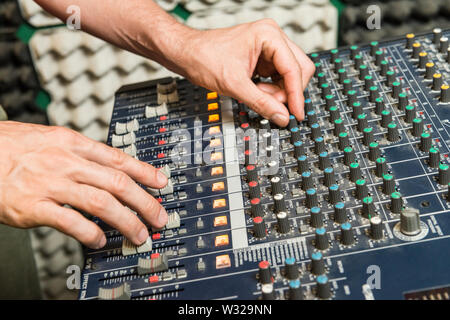 Il concetto di musica. Dettaglio delle mani di un uomo la manipolazione di una console di mixaggio. Foto Stock