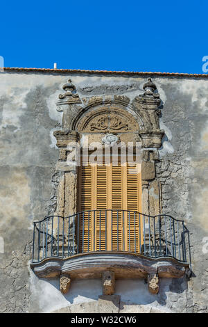 Il barocco mediterraneo balcone chiuso con ante in legno, una ringhiera in ferro su un weathered muro di pietra Foto Stock