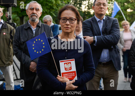 Una donna trattiene una copia della costituzione polacca e una bandiera dell'Unione europea durante una manifestazione di protesta contro la decisione della procura nazionale su Mariusz Krason, davanti a Cracovia la Corte.Mariusz Krason, Cracovia basa procuratore è stato trasferito a Wroclaw. Egli è stato il promotore di una risoluzione in sede di assemblea generale della direzione regionale dell'Ufficio della Procura di Cracovia, in cui egli ha allarmato dalla minaccia di indipendenza del procuratore europeo. Il 18 luglio, la questione dello stato di diritto in Polonia, ai sensi dell'articolo 7 procedura, verrà discusso nella prossima riunione dei ministri UE. Foto Stock