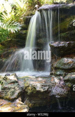 Tranquilla cascata lungo i sentieri attraverso il lussureggiante paesaggio verde con vedute panoramiche Foto Stock