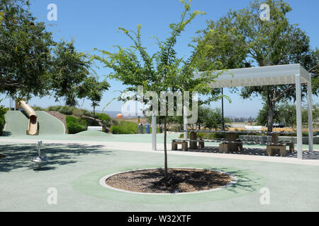 IRIVNE, CALIFORNIA - 11 LUGLIO 2019: Area giochi per bambini nella Bosque Area del Great Park della contea di Orange, con scivoli e giro in mongolfiera in background Foto Stock