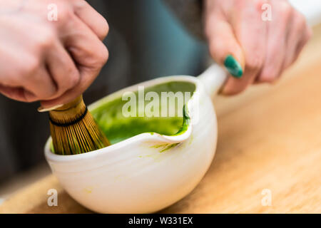 Primo piano della donna azienda giapponese tazza da tè teiera pot e frusta sul tavolo, agitazione e preparare koicha matcha bevanda calda Foto Stock