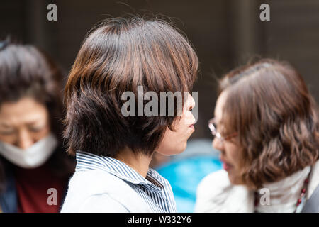 Tokyo, Giappone - 30 Marzo 2019: lato vista di profilo di donna cinese tourist mangiare piatti di pesce di Tsukiji street esterna mercato del pesce Foto Stock