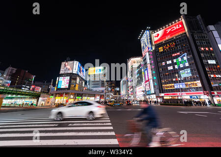 Tokyo, Giappone - Aprile 4, 2019: Shinjuku in centro città con illuminati al neon luminoso luci di notte con il nero con taxi e uomo sulla bicicletta in mo sfocata Foto Stock