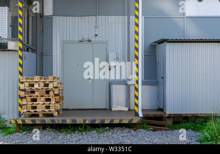 Vista su pallet, contenitori usati, scatole di fronte alla porta del magazzino o dello store Foto Stock