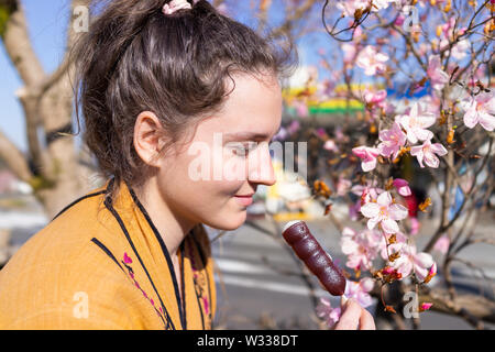 Rosa fiori di ciliegio o susino petali di fiori in primavera a Nikko, Giappone con giovani sorridenti donna tenendo in mano adzuki dango dolce giapponese Foto Stock