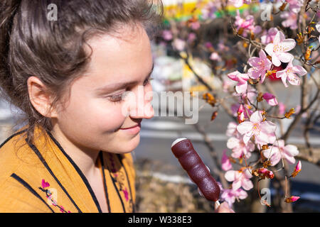 Primo piano di ciliegia o albero di prugna Fiore fiore in primavera a Nikko, Giappone con giovani sorridenti donna tenendo in mano adzuki dango dolce giapponese Foto Stock