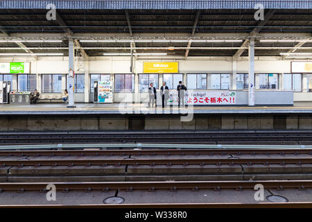 Utsunomiya, Giappone - Aprile 4, 2019: Stazione ferroviaria piattaforma con la gente di affari, imprenditore di attesa per il treno superveloce shinkansen in serata con saluti Foto Stock