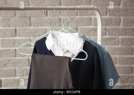 Elegante uniforme scolastica appesa sulla cremagliera contro un muro di mattoni Foto Stock