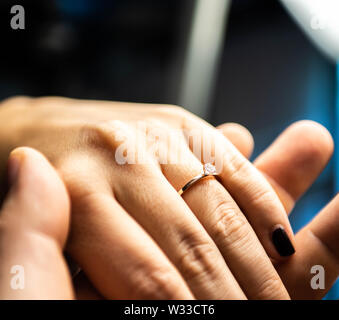 Primo piano delle mani uomo immissione anello di fidanzamento nella donna il dito per amore il matrimonio. Foto Stock