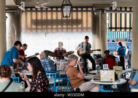 New Orleans, Stati Uniti d'America - 23 Aprile 2018: banda musicale suonando la chitarra e percussioni strumenti concerto live performance presso il Cafe Du Monde beignet famosa e chic Foto Stock