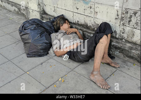 Bangkok, Tailandia - 23 dicembre 2010: un senzatetto giovane uomo che dorme sul marciapiede di thanon Rama 1 Foto Stock