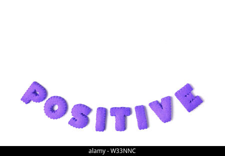 La parola positivo scritto con il colore viola a forma di alfabeto i cookie su sfondo bianco Foto Stock