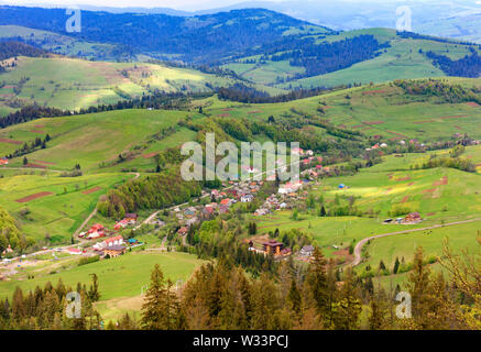 Paesaggio di montagna con vista panoramica del villaggio da un'altezza di sollevamento di montagna in primavera da un picco di montagna, la natura dei Carpazi. Foto Stock