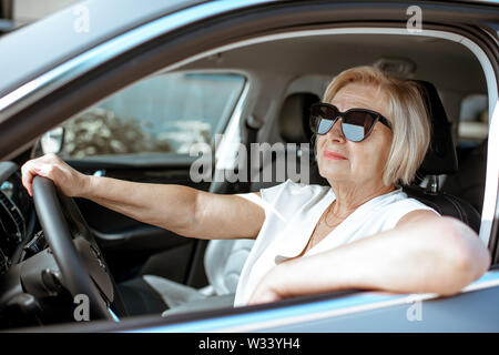 Ritratto di una donna senior conducente seduto in auto moderna Foto Stock