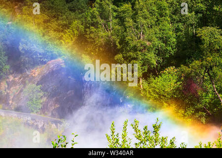 Verde foresta di montagna attraverso la cascata arcobaleno sul modo di Briksdal o ghiacciaio Briksdalsbreen in Olden, Norvegia Foto Stock