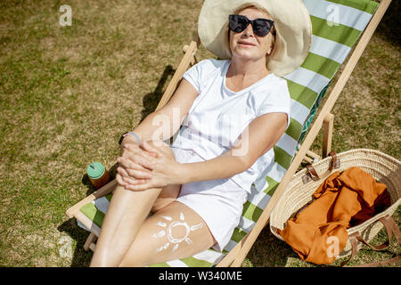 Bella donna senior in bianche vesti sdraiato sul lettino, vista da sopra. Concetto di riposo e di vita spensierata sul pensionamento Foto Stock