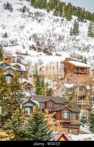 Multipiano residences costruita su una montagna coperta di neve fresca in inverno. Lussureggianti alberi di conifere possono anche essere visto in tutto il case. Foto Stock