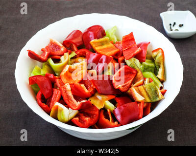 Sweet Pepper, a fette, si trova in una ciotola bianco su uno sfondo scuro, orizzontale Foto Stock