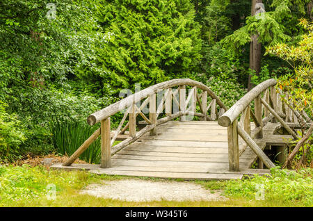 In legno di dimensioni ridotte e pedonale ponte di bicicletta in un parco Foto Stock