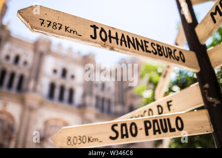 Pole guidepost con più città di destinazione del mondo sulle frecce bastoni in spagnolo. Pone al centro di Malaga Foto Stock