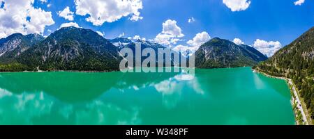 Drone shot, verde smeraldo lago Plansee circondato dalle Alpi Ammergau, distretto di Reutte, Tirolo, Austria Foto Stock