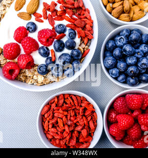 Una sana colazione vegetariana ciotola di muesli con frutta fresca i dadi e yogurt in bianco Bocce Foto Stock