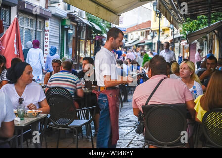 SKOPJE, Macedonia nord-Agosto 22 2019:un cameriere prende ordini presso uno dei molti piccoli ristoranti nel Vecchio Bazar quartiere di Skopje. Foto Stock